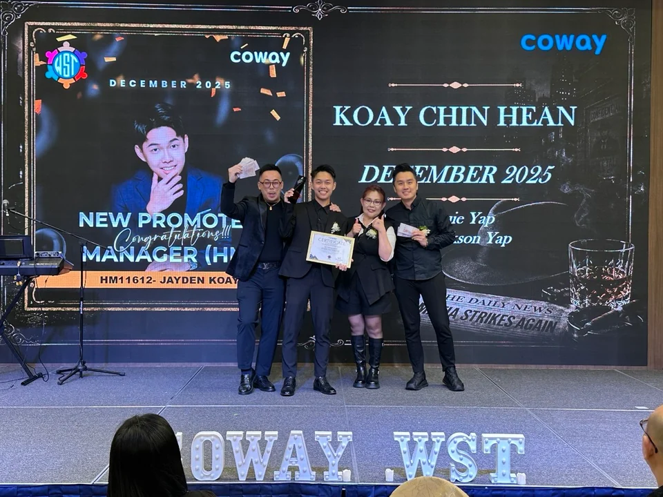 Four people holding a certificate on a promotion stage